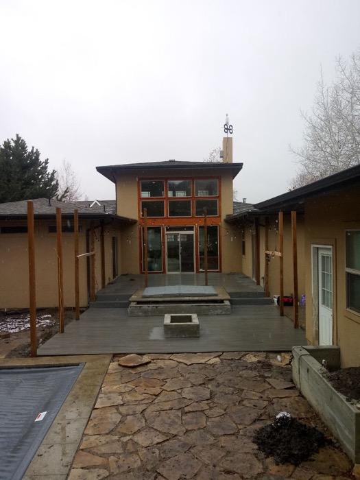 Composite deck with a square fire pit set into it, a hot tub in the raised section by the doors and a flagstone entryway running up to it.