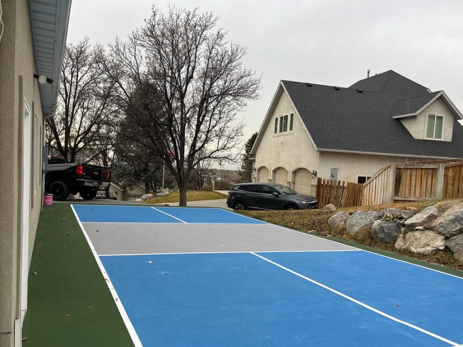 Multi-sport court in Holladay beside the pool house, sky blue zones with a grey kitchen and grass green apron.