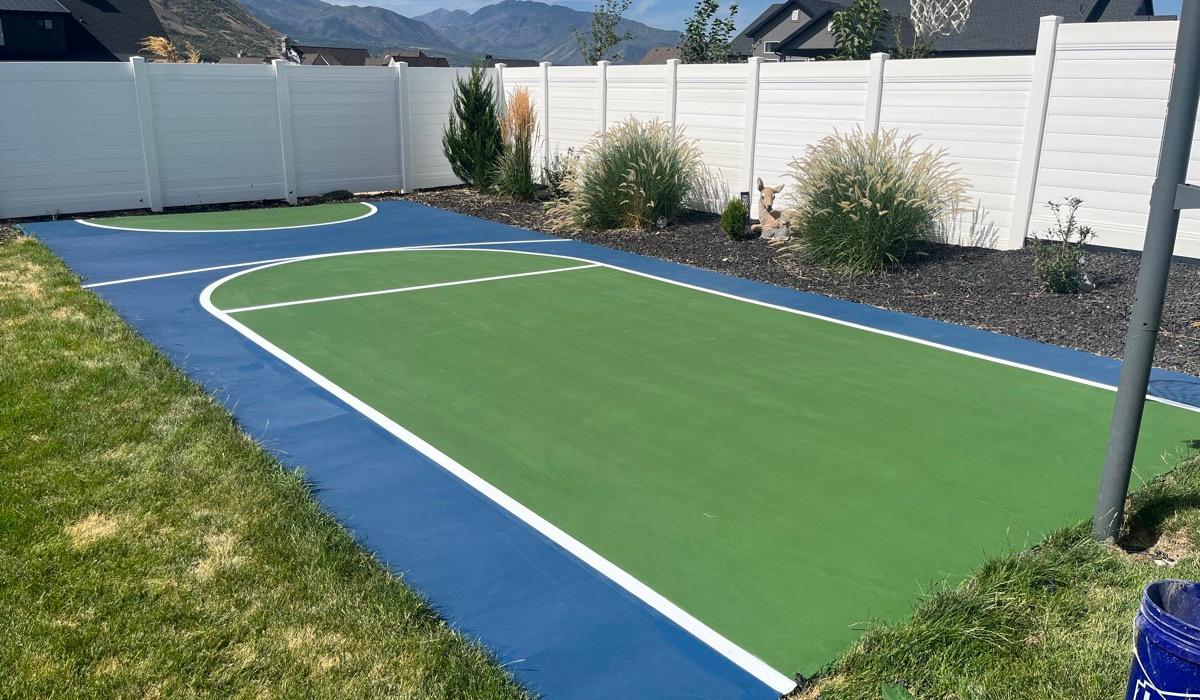 Backyard basketball half court in Spanish Fork, green key inside a navy surround