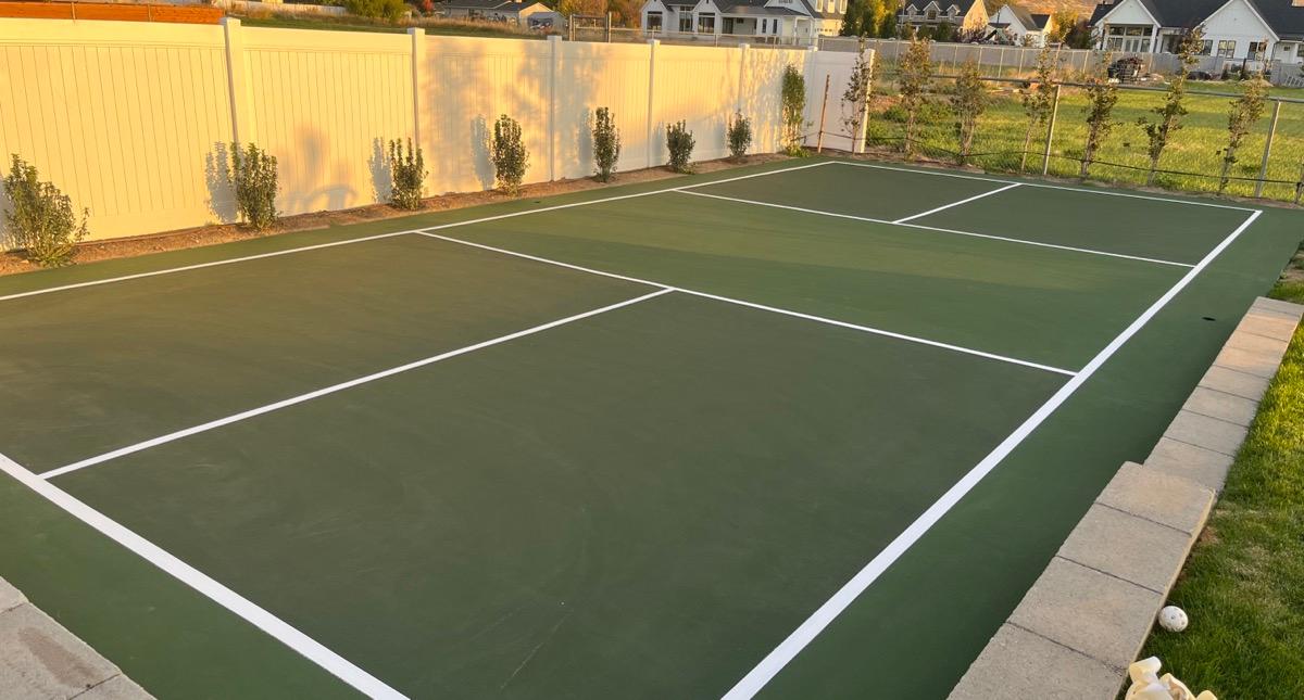 Pickleball court in Highland at sunset, built against a cinderblock retaining wall.